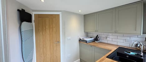 A compact kitchen with a wooden door, a sink, and cabinets.