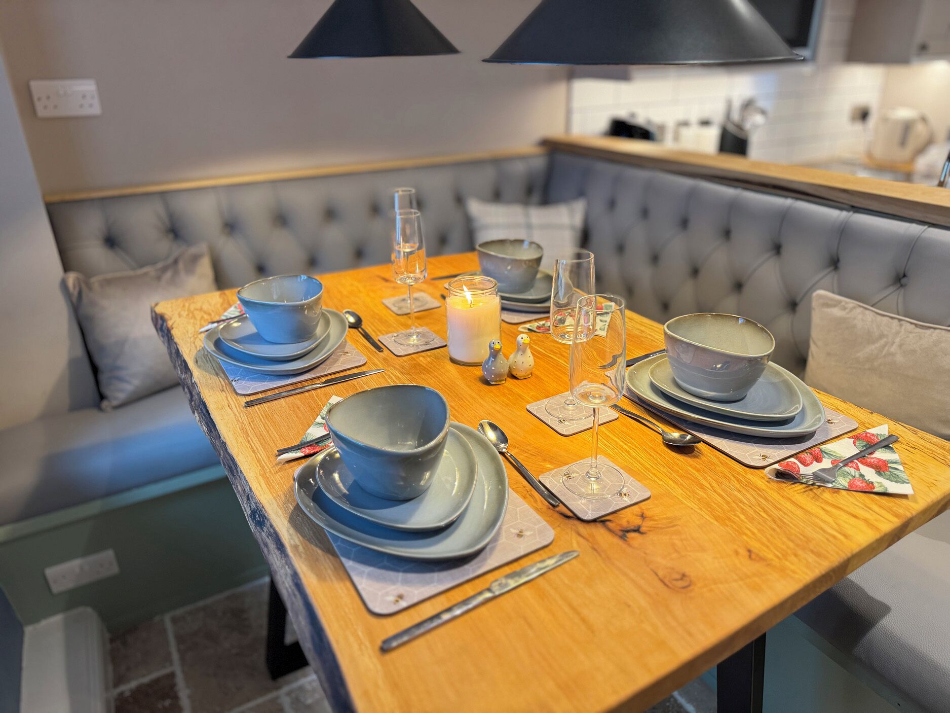 A dining table set with blue plates, glasses, and cutlery, with a candle and salt and pepper shakers on the table.