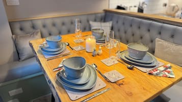 A dining table set with blue plates, glasses, and cutlery, with a candle and salt and pepper shakers on the table.