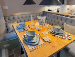 Ein Esstisch mit blauem Geschirr, Gläsern und Besteck, mit Kerze und Salz- und Pfefferstreuern.