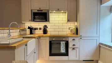 A kitchen with white cabinets, a microwave, an oven, a sink, and a toaster.