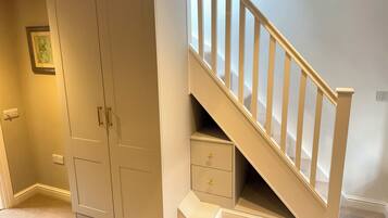 A room with a built-in wardrobe, a staircase, and a small bedside table.
