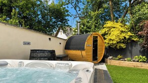 A hot tub with a wooden barrel sauna, a 'COLD PLUNGE' sign, and a 'VERY HOT' sign. - Railway Cottage (Oswestry)