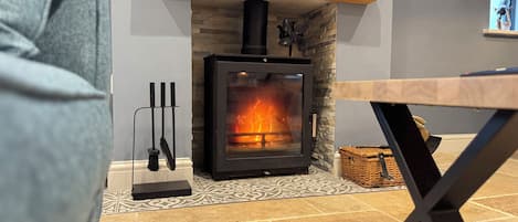A modern room with a stone fireplace, a wooden shelf above it, and a table with a metal frame.