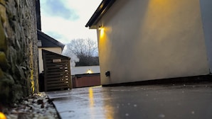 A stone wall, a wooden gate, and a white building with a flat roof. - Railway Cottage (Oswestry)