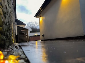 Un muro de piedra, un portón de madera y un edificio blanco con techo plano.