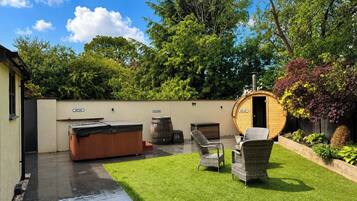 A spa area with a hot tub, seating, and a wooden barrel.