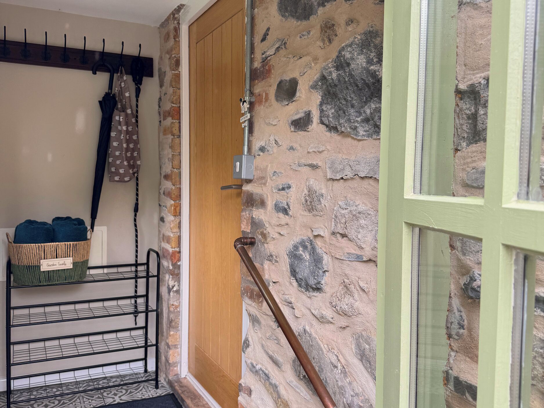 A stone wall, a wooden door, a metal rack with towels, and a metal staircase.
