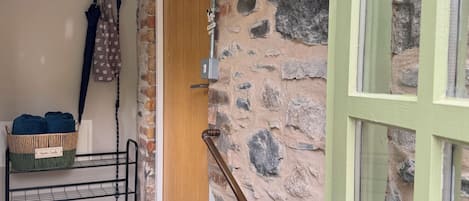 A stone wall, a wooden door, a metal rack with towels, and a metal staircase.
