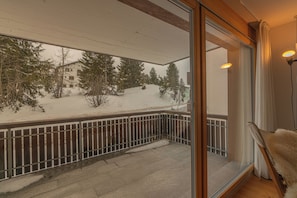 Ein Balkon mit Blick auf eine verschneite Landschaft, einer Brüstung und einem Stuhl.