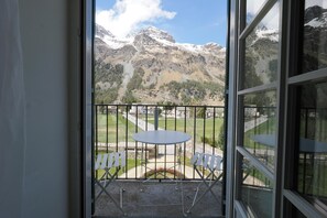 A balcony with a view of snow-capped mountains, a table, and chairs. - Residenza Alpenrose – A stylish studio with views of Lake Sils (Sils/Segl Maria)