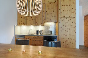 Eine Küche mit Holzschränken, einem Edelstahl-Geschirrspüler und einem Holzesstisch mit Kerzen.