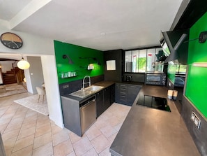 Cozinha moderna com parede verde decorativa, forno embutido e pia.