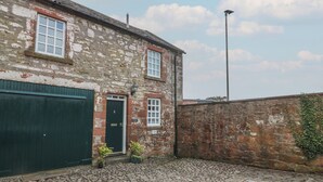 A stone building with a green door, a window, and a cobblestone courtyard. - The Old Coach House (Lochmaben)