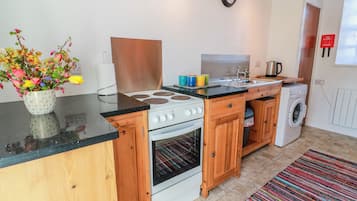 A compact kitchen with a stove, oven, sink, and washing machine.