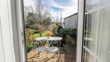 Un patio con una mesa y sillas, una planta en maceta y vistas de un jardín y una casa.