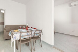 A dining area with a table set for four, a sofa, and a door leading to another room. - Borgo Climmena - Bilo accessibile (Manduria)