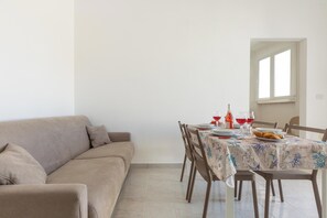 Ein Essbereich mit einem Tisch für vier Personen, einer Couch und einem Fenster mit Tageslicht.