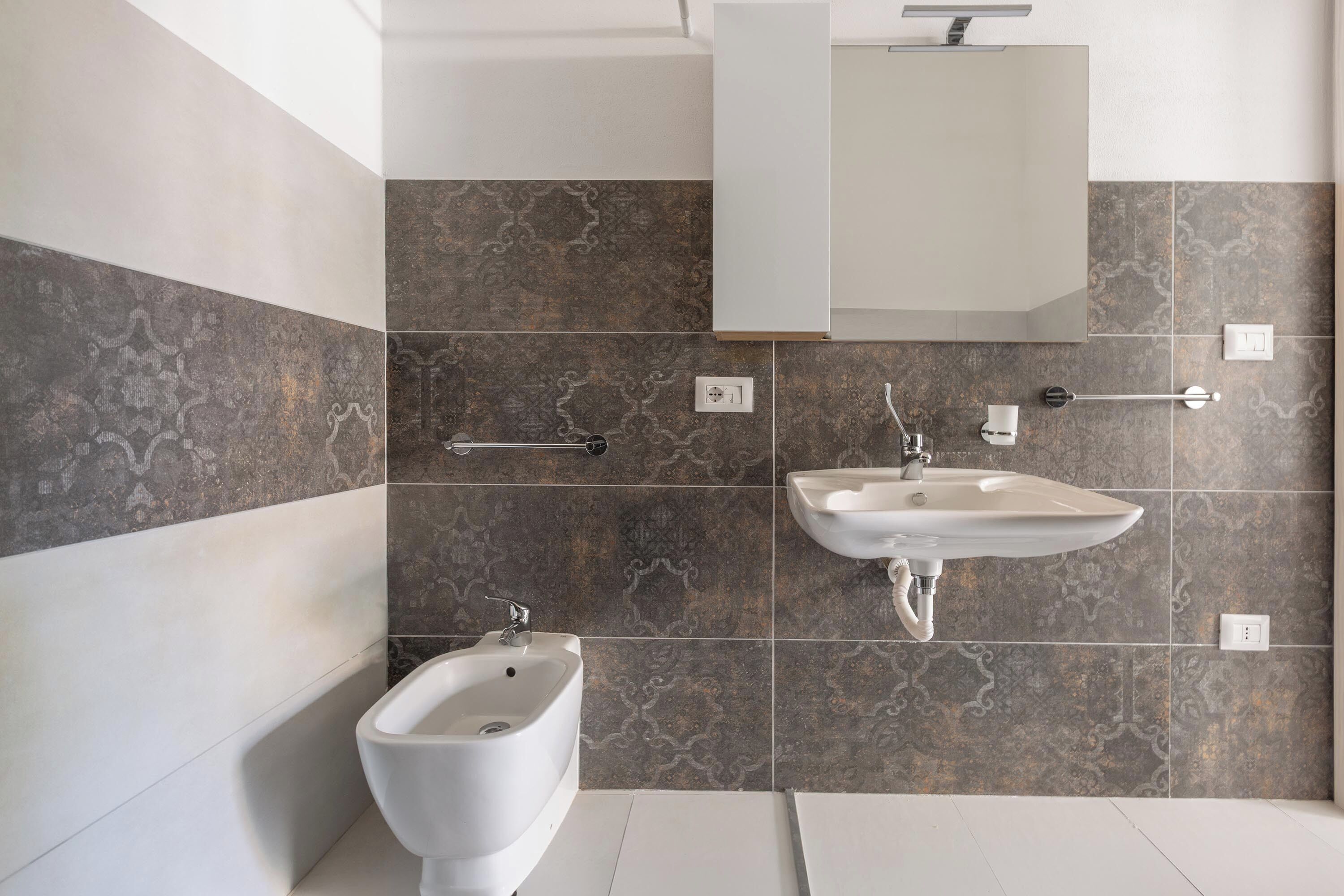 A modern bathroom with a bidet, a sink, and a mirror.
