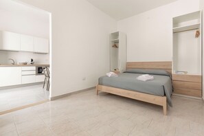 A bedroom with a bed, a bedside table, a wardrobe, and a bathroom with a mirror. - Borgo Climmena - Bilo accessibile (Manduria)
