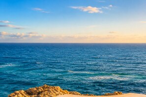Une vue sur la côte, avec une mer bleue et limpide et un rivage rocheux.