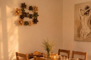 Ein Esstisch mit Stühlen, eine Blumenvase, ein Brotkorb und eine Kerze.