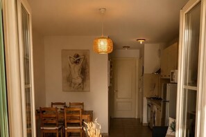 Un couloir comprenant un coin repas, un tableau, un luminaire suspendu et un espace cuisine.