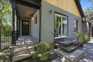 Ein modernes Haus mit Holzfassade, einer Veranda und einem kleinen Garten.