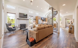 A modern living room with a fireplace, sofa, and dining area.