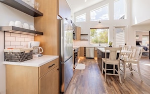 A modern kitchen with a refrigerator, coffee maker, and wooden cabinets.