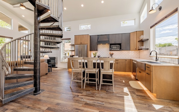 Una cocina moderna con una isla central, suelo de madera y una escalera en espiral.