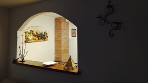 A wall-mounted mirror with a rustic arch design, a small table, and a decorative item. - Visit Lu Bagnu – Affordable Holiday Apartment Near Castelsardo (Lu Bagnu)
