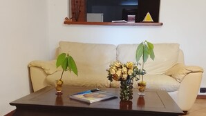 A living room with a dark wooden coffee table, a beige sofa, and a small shelf with decorative items. - Visit Lu Bagnu – Affordable Holiday Apartment Near Castelsardo (Lu Bagnu)