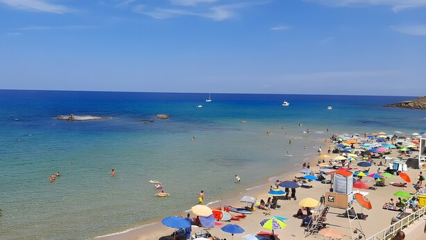 A beach with clear water, people swimming, and colorful umbrellas. - Visit Lu Bagnu – Affordable Holiday Apartment Near Castelsardo (Lu Bagnu)