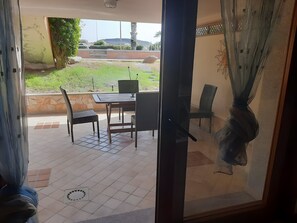 Una habitación con puerta corrediza de vidrio que da a un patio exterior con mesa y sillas.