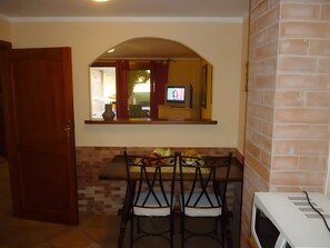 Una cocina con comedor, televisor y microondas.