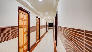 Um corredor longo e estreito com portas de madeira e paredes revestidas de azulejos brancos.