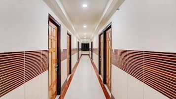 A long, narrow hallway with doors on both sides, leading to a dark room at the end.