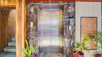 An elevator with a marble wall and a reception sign indicating floor locations.