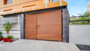 Um portão de madeira dupla com grade de metal, um caminho de acesso de concreto e vasos de plantas.