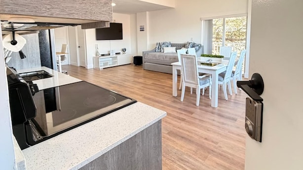 Une cuisine moderne dotée d’une cuisinière intégrée, un coin repas avec une table et des chaises, et un salon avec un canapé.