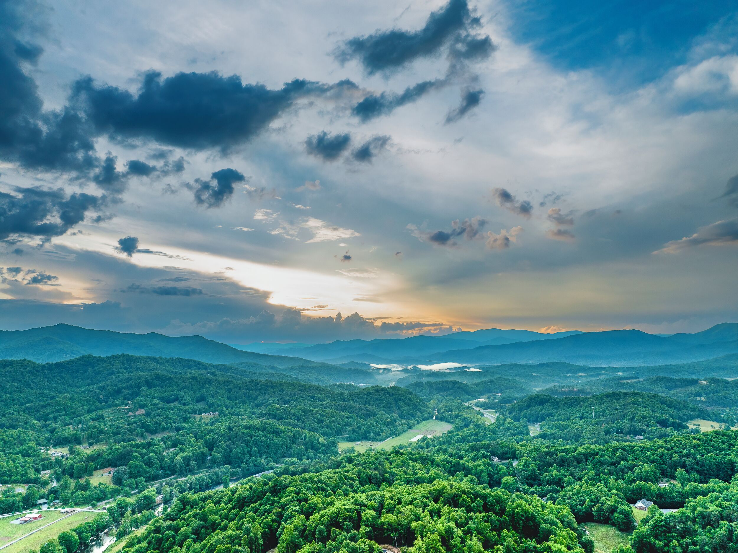 A panoramic view of a mountainous landscape with dense forests and a clear sky.