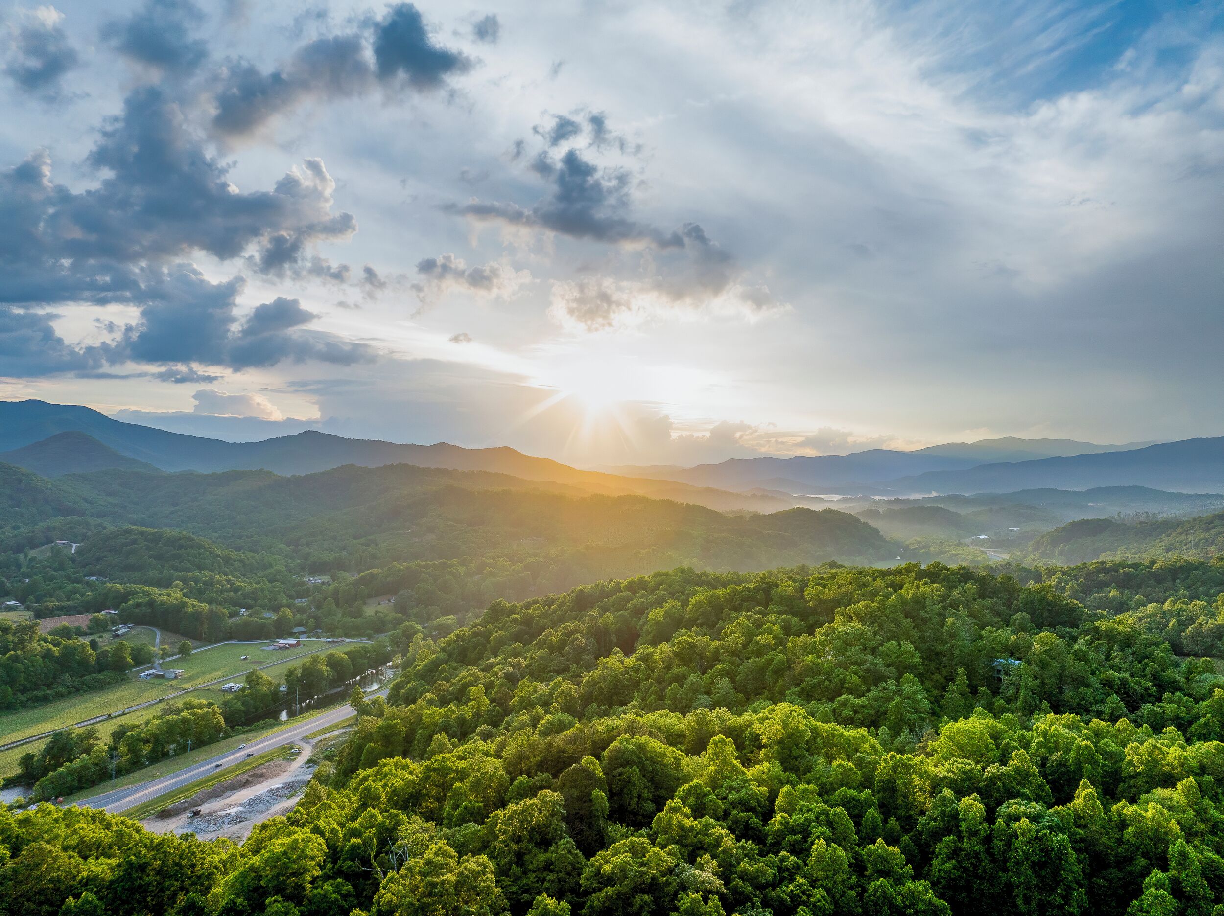 A mountainous landscape with a road and greenery.