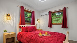 A bedroom with a red bedspread, wooden headboard, two bedside tables, a nightstand, a tray with breakfast, and a window with curtains. - Bryson City Cabin · Sleeps 5 · Pets OK · Fire Pit (Whittier)