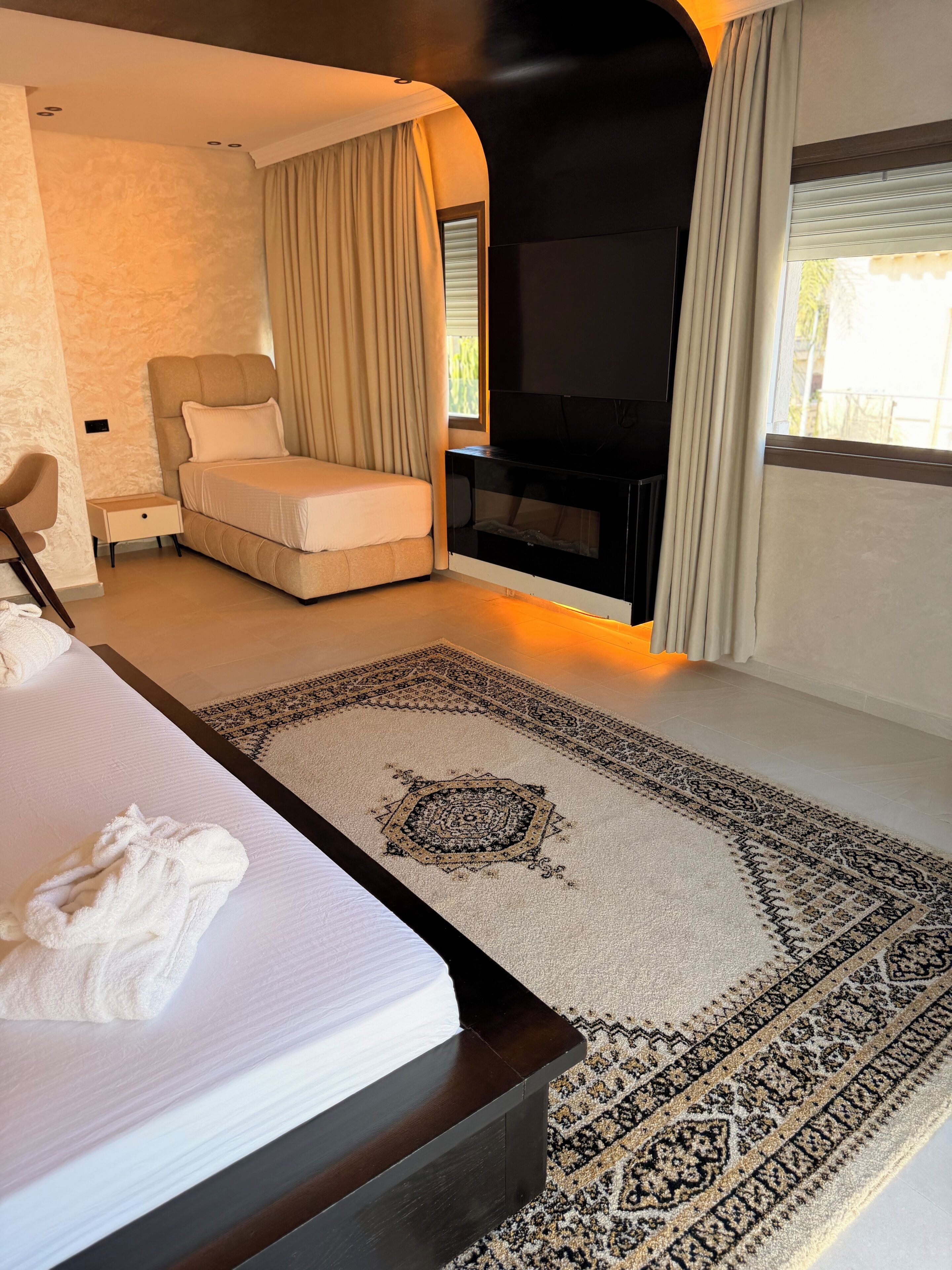 A hotel room with a bed, a seating area, a television, and a large window.