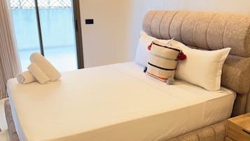 A bedroom with a large bed, a wooden nightstand, and a decorative wall piece.