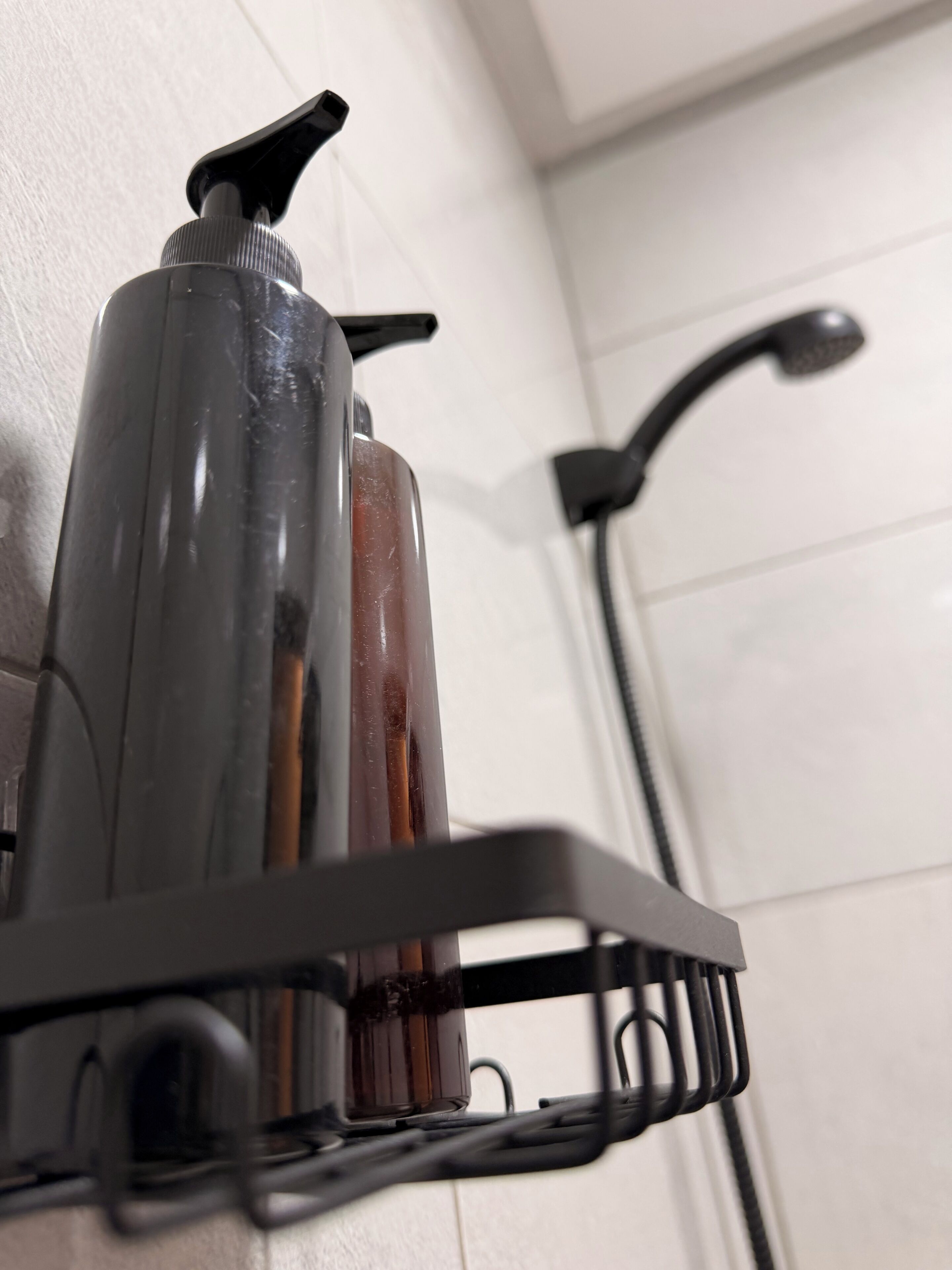 A bathroom with a shower, a towel rack, and a soap dispenser.