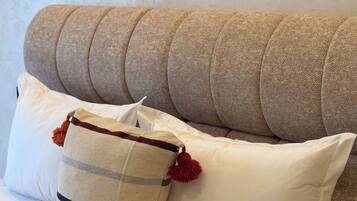 A sofa with multiple cushions, a striped pillow, and a pom-pom.