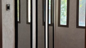 Una habitación con un ventanal grande, una puerta y un interruptor de luz en la pared.