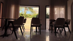 A modern interior with a seating area, a glass door leading outside, and a view of greenery. - Riad Elizabeth (Nouaceur)